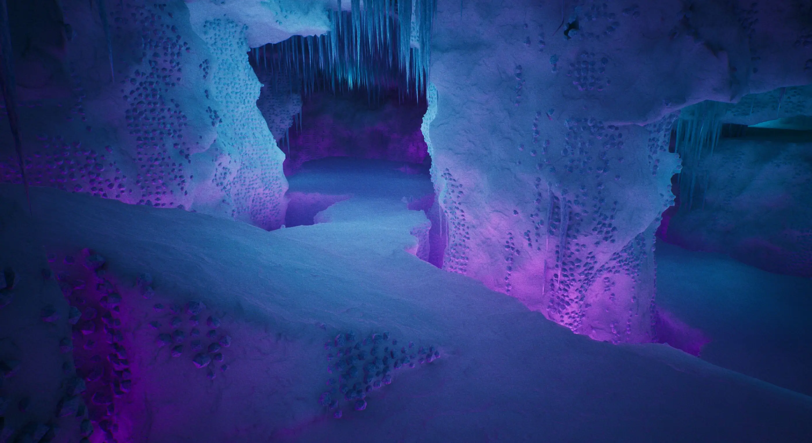 A voxel ice cave lit in blue and purple, with a passage leading deeper in